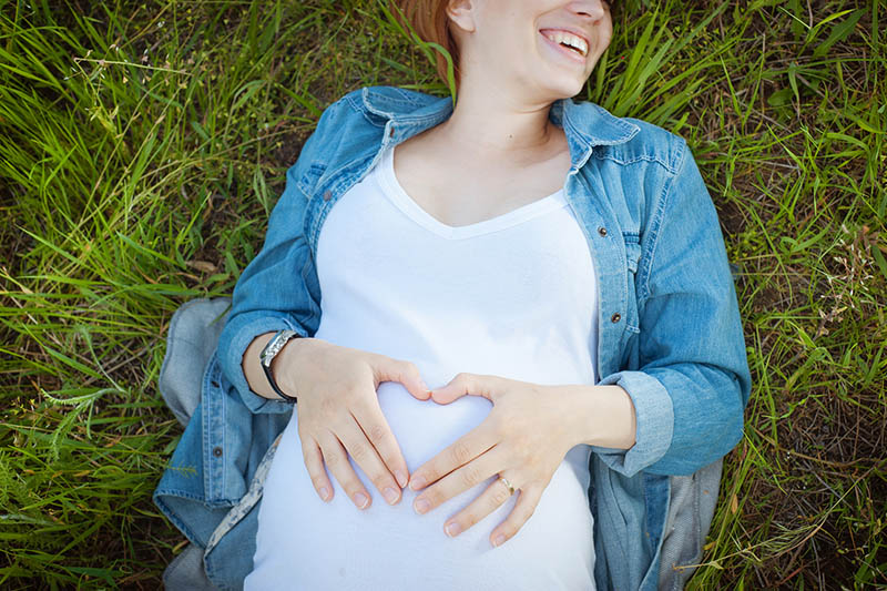 happy pregnant woman laying on the grass